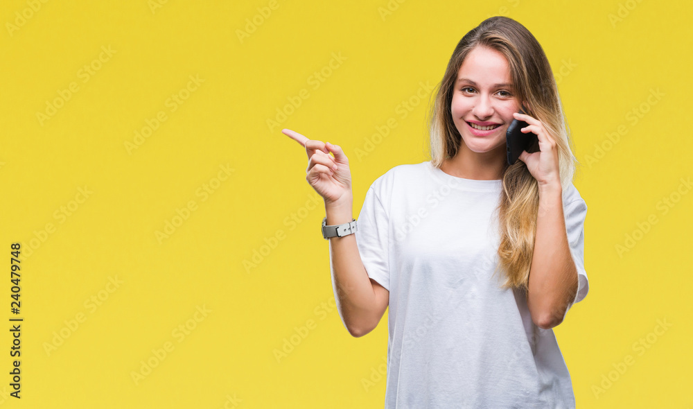 Young beautiful blonde woman calling using smartphone over isolated background very happy pointing with hand and finger to the side Young beautiful blonde woman calling using smartphone over isolated background very happy pointing with hand and finger to the side