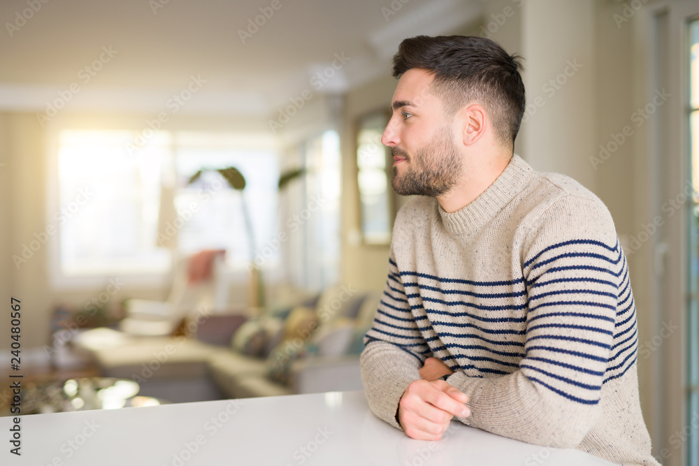 Young handsome man at home looking to side, relax profile pose with natural face with confident smile. Young handsome man at home looking to side, relax profile pose with natural face with confident smile.