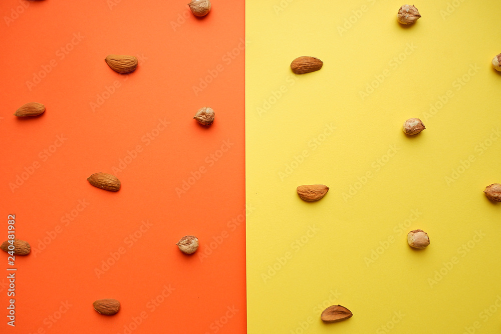 Hazelnut and almond pattern on a yellow-orange background, top view Hazelnut and almond pattern on a yellow-orange background, top view
