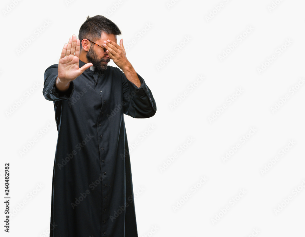 Adult hispanic catholic priest man over isolated background covering eyes with hands and doing stop gesture with sad and fear expression. Embarrassed and negative concept.
