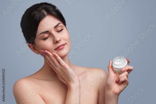 Young woman smearing cream on face