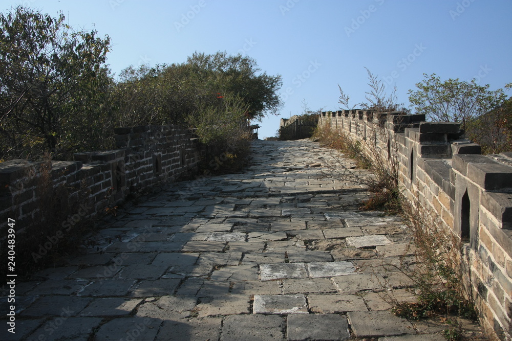 The road to the Great Wall of China in the area of Munteanu among the autumn forest, the paved surface of the wall suitable for riders.