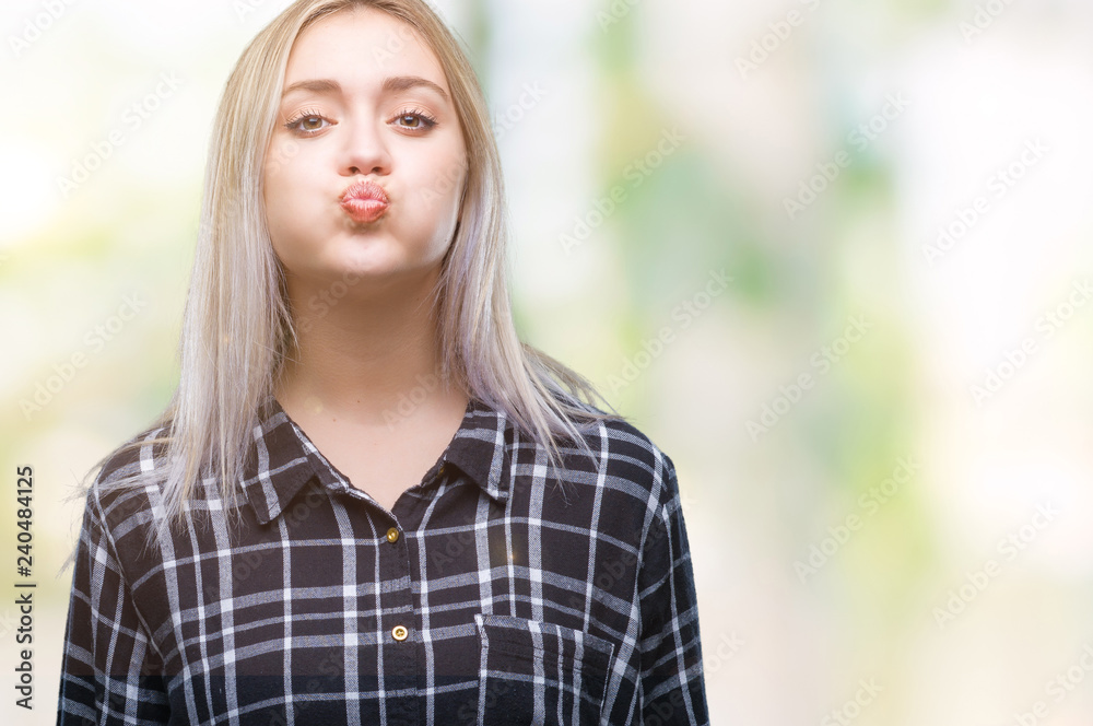 Young blonde woman over isolated background puffing cheeks with funny face. Mouth inflated with air, crazy expression. Young blonde woman over isolated background puffing cheeks with funny face. Mouth inflated with air, crazy expression.
