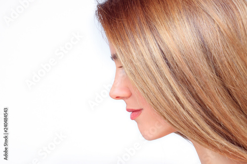 Beautiful woman face with long blond hair from the side looks down
