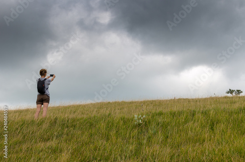Young woman hiker taking photos using a mobile phone in the countryside