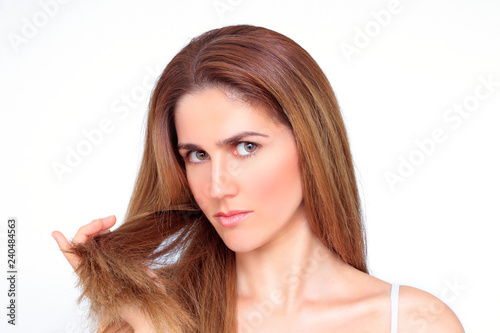 Beautiful stressed woman showing her damaged hair