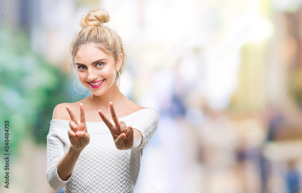 Young beautiful blonde and blue eyes woman over isolated background smiling looking to the camera showing fingers doing victory sign. Number two.