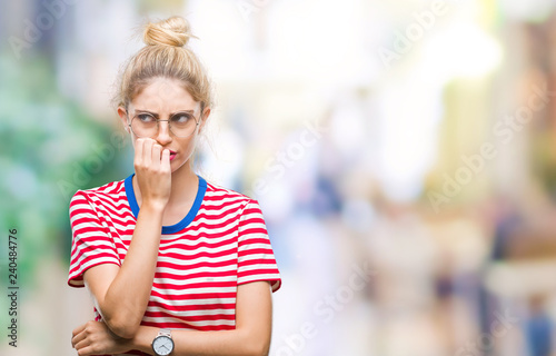 Young beautiful blonde woman wearing glasses over isolated background looking stressed and nervous with hands on mouth biting nails. Anxiety problem.