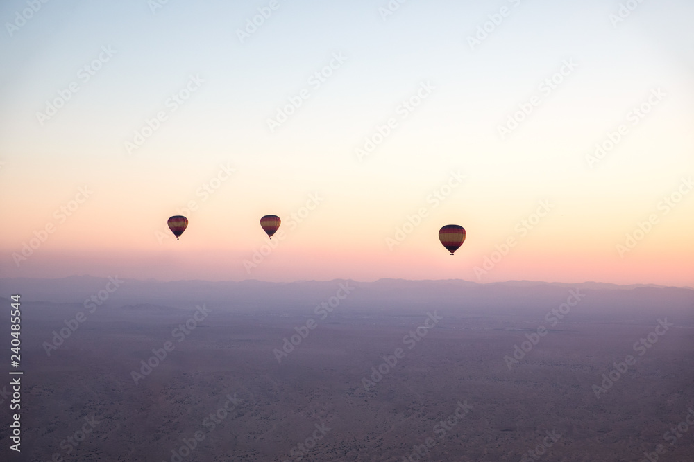 Air balloons over desert during sunrise.