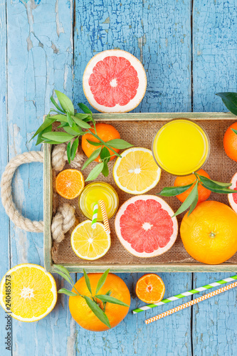 Set of different fruits and glass with fresh orange juice, wooden tray