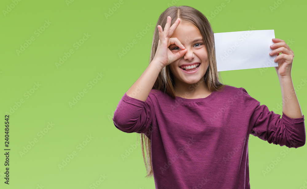 Young beautiful girl holding blank paper card over isolated background with happy face smiling doing ok sign with hand on eye looking through fingers Young beautiful girl holding blank paper card over isolated background with happy face smiling doing ok sign with hand on eye looking through fingers