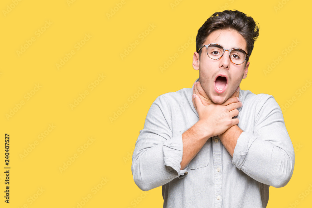 Young handsome man wearing glasses over isolated background shouting and suffocate because painful strangle. Health problem. Asphyxiate and suicide concept.