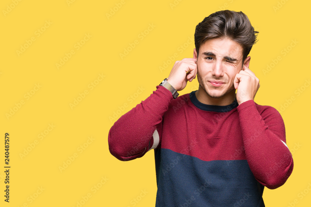 Young handsome man over isolated background covering ears with fingers with annoyed expression for the noise of loud music. Deaf concept.