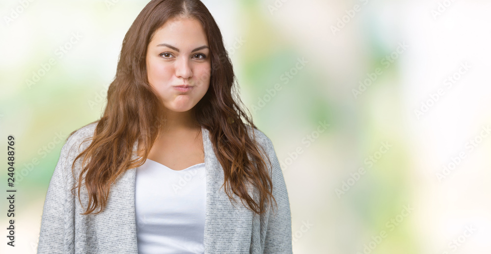 Beautiful plus size young woman wearing winter jacket over isolated background puffing cheeks with funny face. Mouth inflated with air, crazy expression. Beautiful plus size young woman wearing winter jacket over isolated background puffing cheeks with funny face. Mouth inflated with air, crazy expression.
