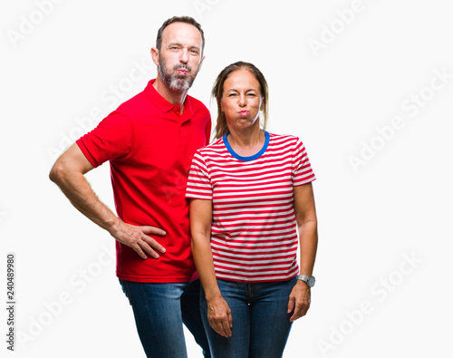 Middle age hispanic couple in love over isolated background puffing cheeks with funny face. Mouth inflated with air, crazy expression.