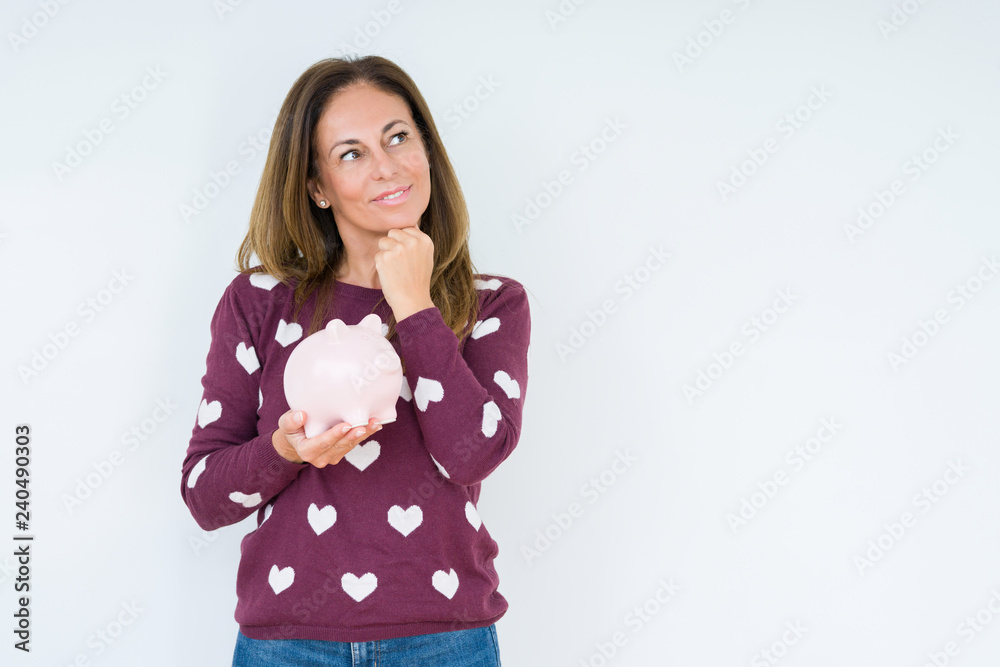 Middle age woman holding piggy bank over isolated background serious face thinking about question, very confused idea Middle age woman holding piggy bank over isolated background serious face thinking about question, very confused idea