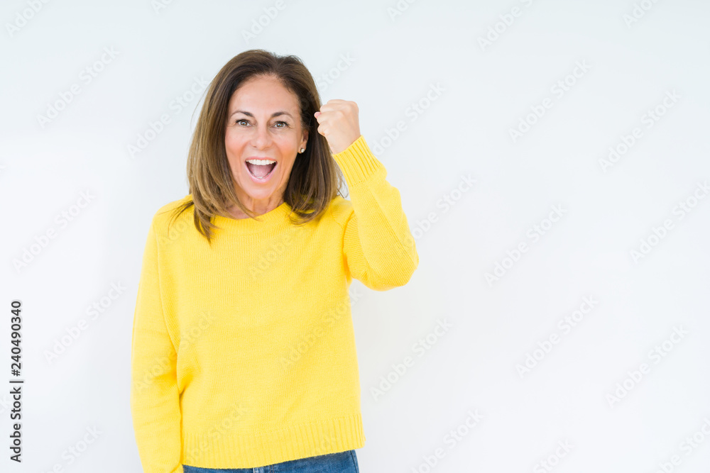 Beautiful middle age woman wearing yellow sweater over isolated background angry and mad raising fist frustrated and furious while shouting with anger. Rage and aggressive concept. Beautiful middle age woman wearing yellow sweater over isolated background angry and mad raising fist frustrated and furious while shouting with anger. Rage and aggressive concept.