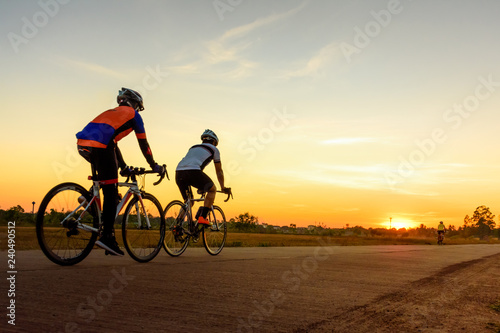 Men ride bicycles on the road with beautiful colorful sunset sky. Sport and active life concept.