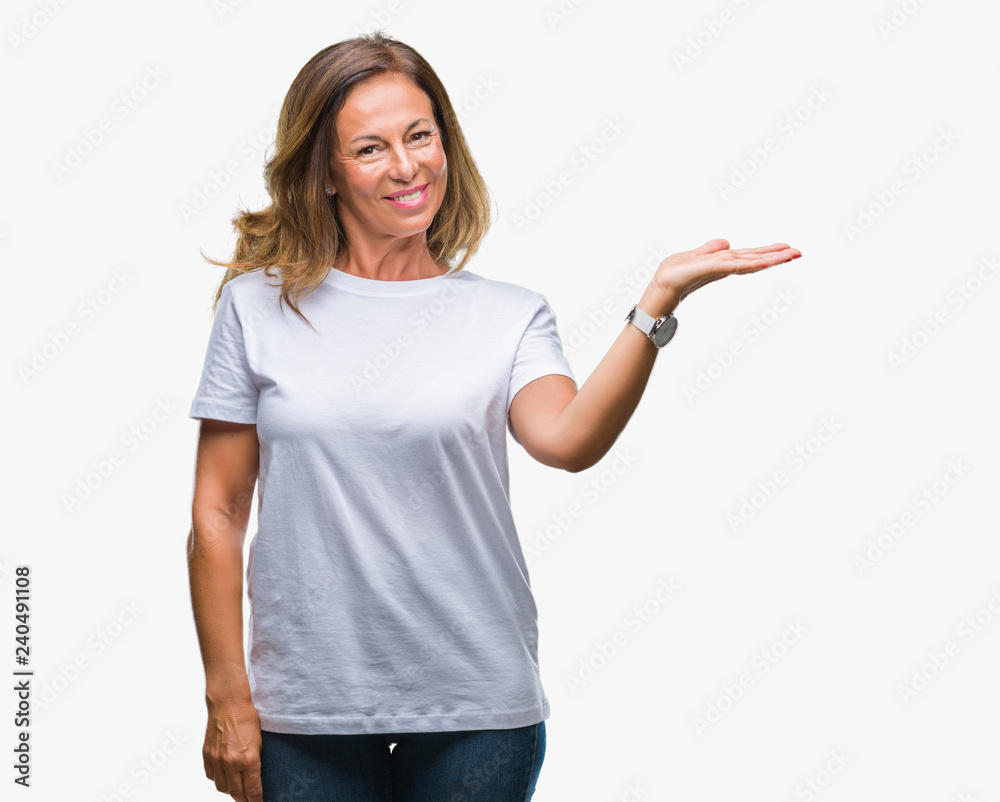 Middle age senior hispanic woman over isolated background smiling cheerful presenting and pointing with palm of hand looking at the camera. Middle age senior hispanic woman over isolated background smiling cheerful presenting and pointing with palm of hand looking at the camera.