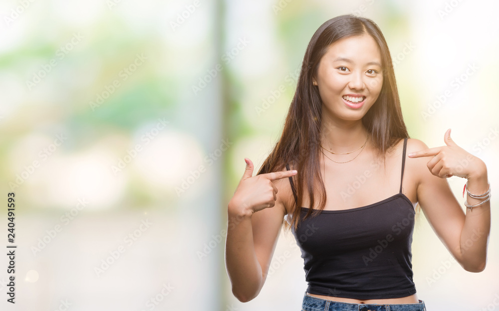 Young asian woman over isolated background looking confident with smile on face, pointing oneself with fingers proud and happy.
