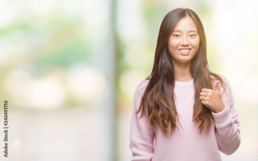 Young asian woman over isolated background doing happy thumbs up gesture with hand. Approving expression looking at the camera with showing success.