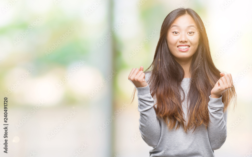 Young asian woman over isolated background celebrating surprised and amazed for success with arms raised and open eyes. Winner concept. Young asian woman over isolated background celebrating surprised and amazed for success with arms raised and open eyes. Winner concept.