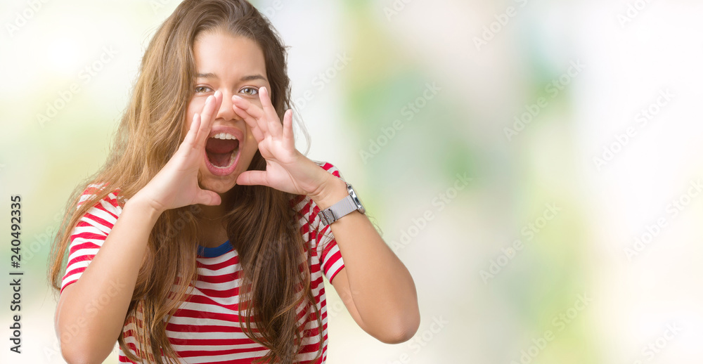 Young beautiful brunette woman wearing stripes t-shirt over isolated background Shouting angry out loud with hands over mouth
