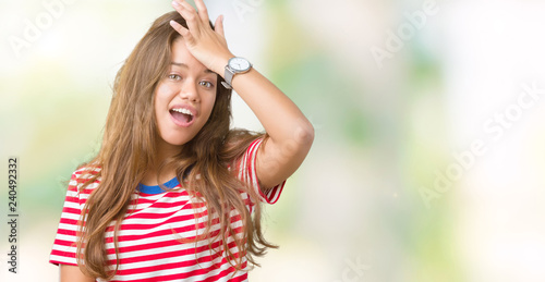 Young beautiful brunette woman wearing stripes t-shirt over isolated background surprised with hand on head for mistake, remember error. Forgot, bad memory concept.