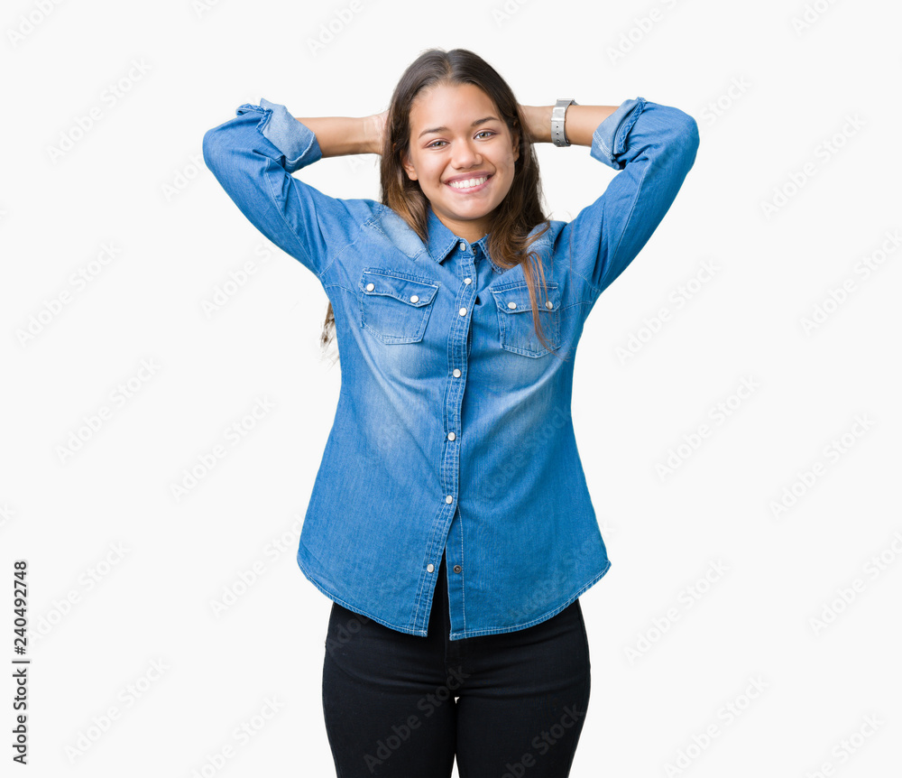 Young beautiful brunette woman wearing blue denim shirt over isolated background Relaxing and stretching with arms and hands behind head and neck, smiling happy Young beautiful brunette woman wearing blue denim shirt over isolated background Relaxing and stretching with arms and hands behind head and neck, smiling happy