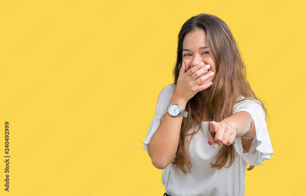 Young beautiful brunette business woman over isolated background Laughing of you, pointing to the camera with finger hand over mouth, shame expression Young beautiful brunette business woman over isolated background Laughing of you, pointing to the camera with finger hand over mouth, shame expression