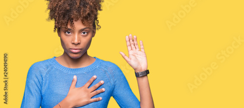 Beautiful young african american woman over isolated background Swearing with hand on chest and open palm, making a loyalty promise oath