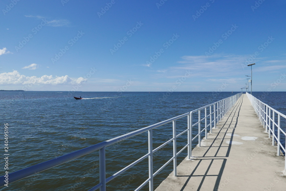 Perspective view of jetty with LED street light with solar cell on clear blue sky.