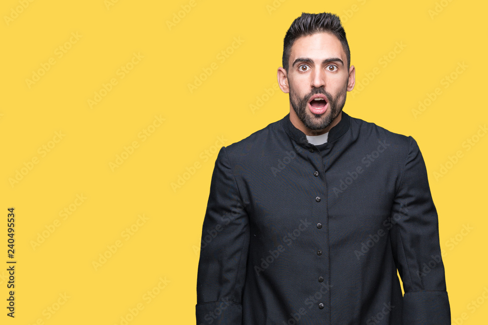 Obraz premium Young Christian priest over isolated background afraid and shocked with surprise expression, fear and excited face.