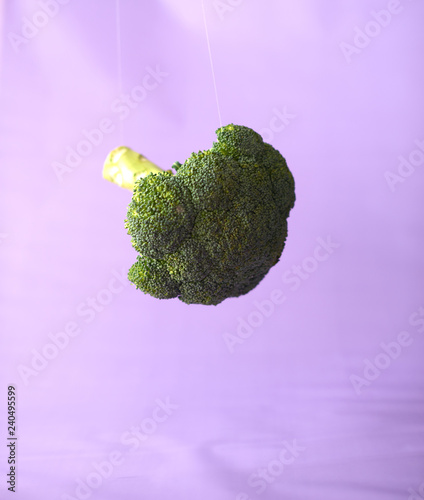 Fresh broccoli in the air on a purple background photo