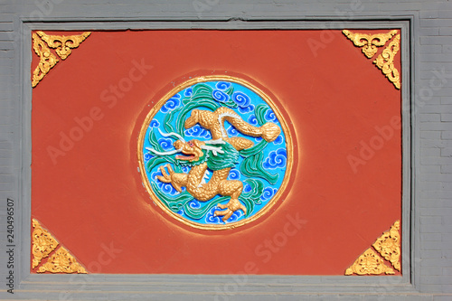 Coloured glaze sculpture on red wall in a temple