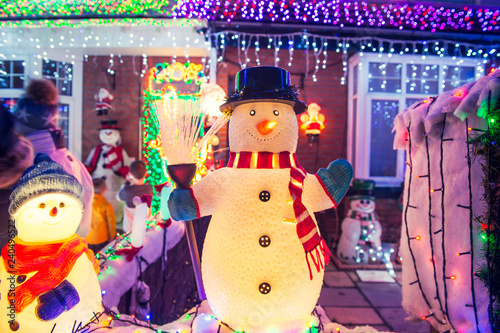 Decorative snowmen with lights and shiny outdoor Christmas decorations at night. Merry Xmas and New Year outside exterior decor. Selective focus, copy space. photo