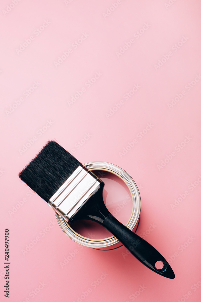 Brush with black handle on open can of pink paint on pastel background. Renovation concept. Top view. Brush with black handle on open can of pink paint on pastel background. Renovation concept. Top view.