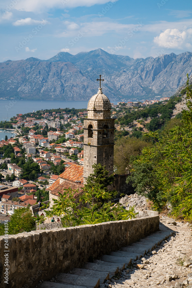 Beautiful scenery on the way up the stairs to the castle of San Giovanni, Kotor. Behind the old church you can see the old town and the bay of Kotor, Montenegro.