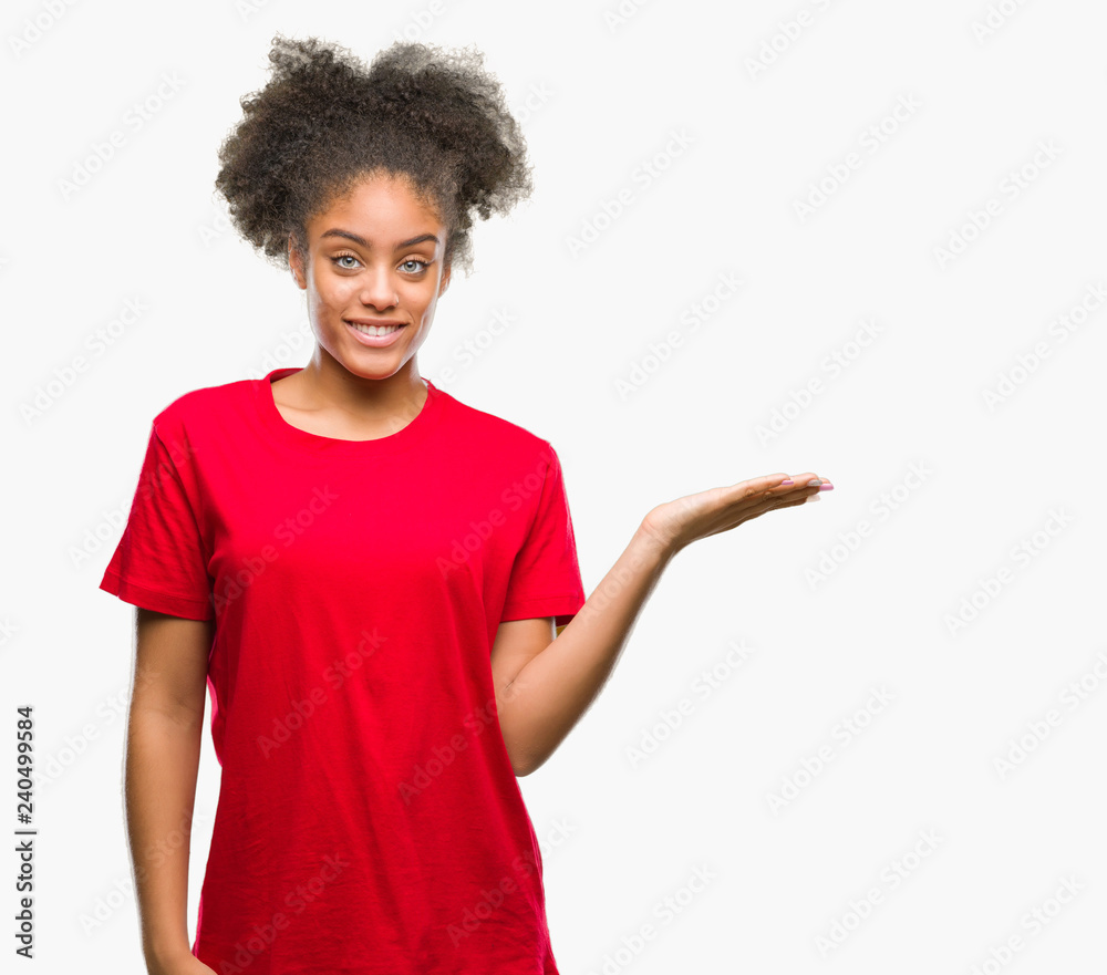 Young afro american woman over isolated background smiling cheerful presenting and pointing with palm of hand looking at the camera. Young afro american woman over isolated background smiling cheerful presenting and pointing with palm of hand looking at the camera.