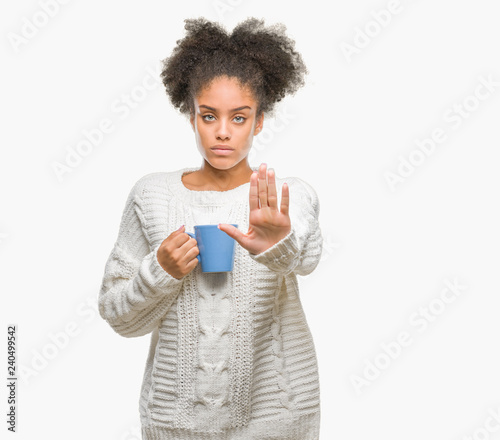 Young afro american woman driking cup of coffee over isolated background with open hand doing stop sign with serious and confident expression, defense gesture