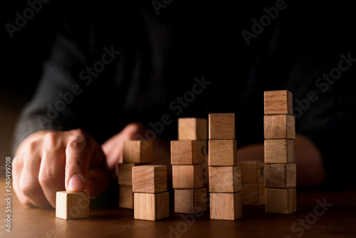 business man try to choose wood block from others on wooden table and black background business organization startup concept