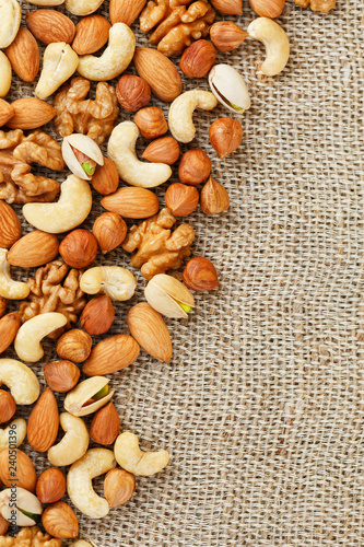 Mix of nuts lying on a background of brown cloth burlap.