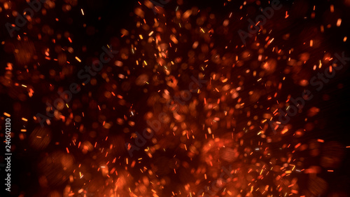 Burning red hot sparks fly from large fire in the night sky. Beautiful abstract background on the theme of fire, light and life. Burning embers glowing flying away particles over black background.