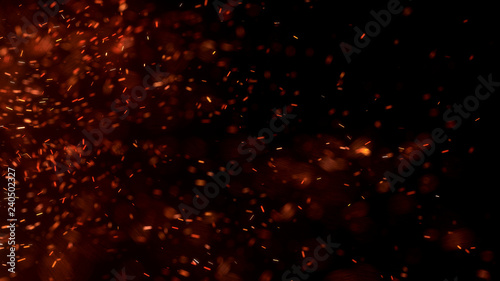 Burning red hot sparks fly from large fire in the night sky. Beautiful abstract background on the theme of fire, light and life. Burning embers glowing flying away particles over black background. photo