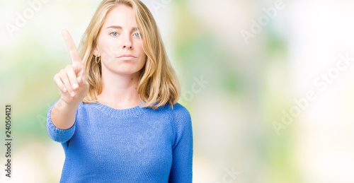 Fototapeta Naklejka Na Ścianę i Meble -  Beautiful young woman wearing blue sweater over isolated background Pointing with finger up and angry expression