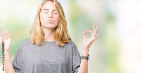 Beautiful young woman wearing oversize casual t-shirt over isolated background relax and smiling with eyes closed doing meditation gesture with fingers. Yoga concept.