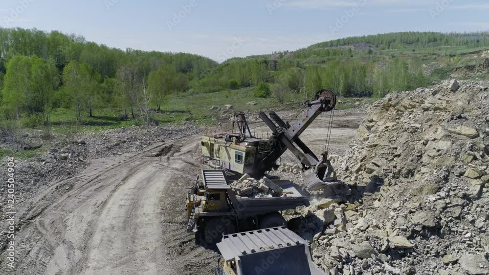 Aerial view. Excavator loads stones into a dump truck. UHD Aerial view. Excavator loads stones into a dump truck. UHD