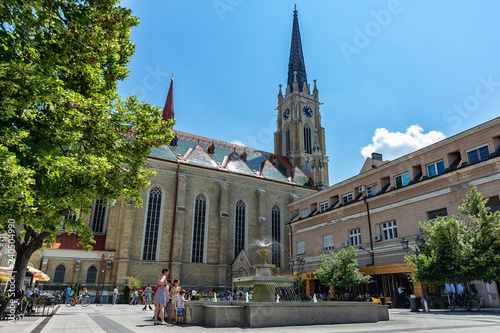 Novi Sad, Serbia - May 27, 2018: View of one square with fountain and old buildings located behind at the Catholic Church `The Name of Mary Church