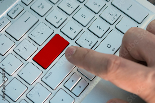 Man hand push button. Red button on grey silver laptop keyboard. Ccopy space to test photo