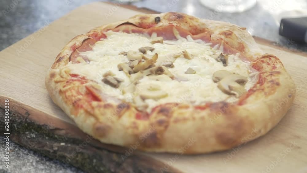 putting pizza on a wooden plate and placing basil leave on top putting pizza on a wooden plate and placing basil leave on top